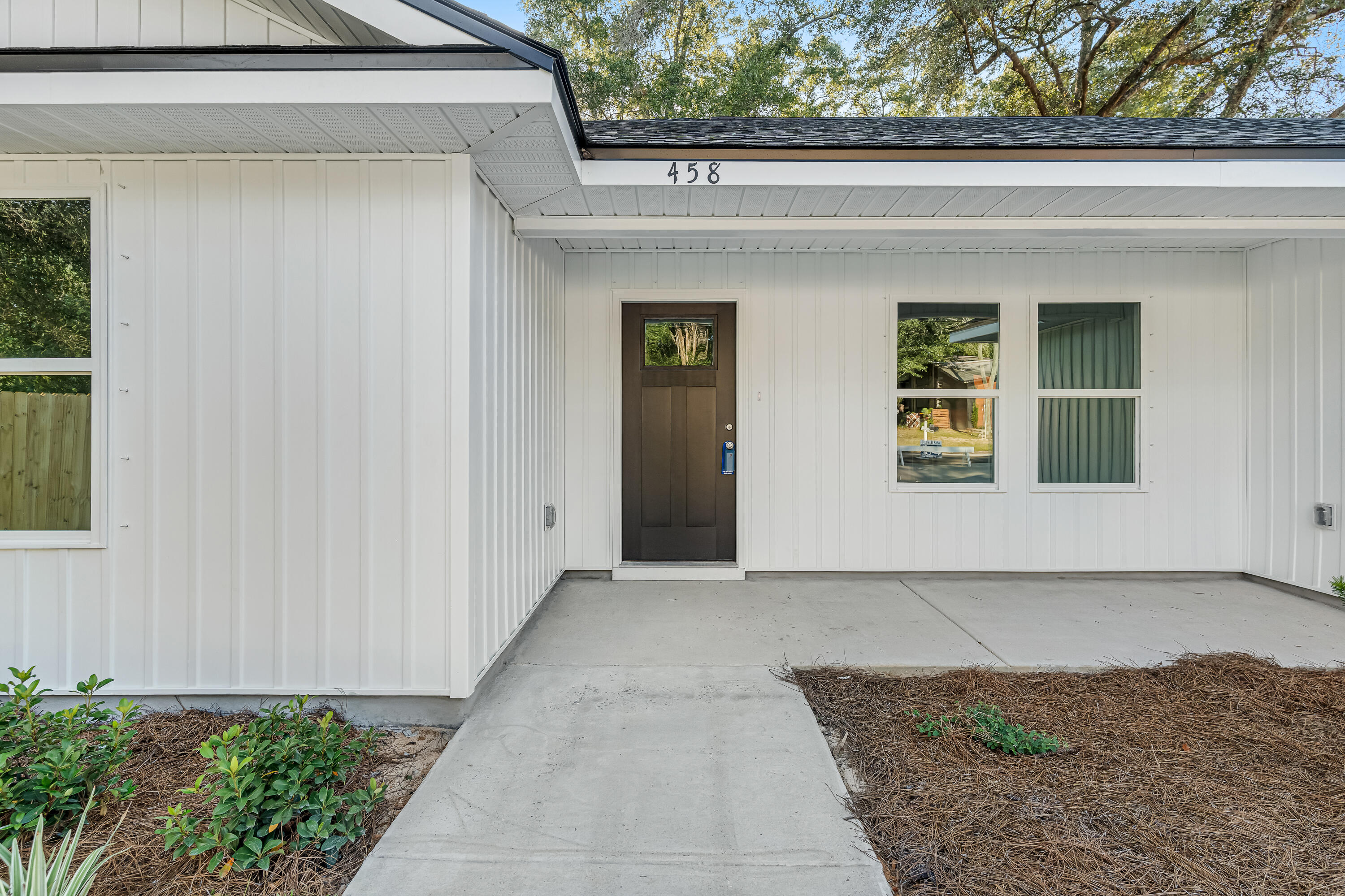 White-sided home with a covered entry, dark front door, and concrete walkway; number 458 above the door.