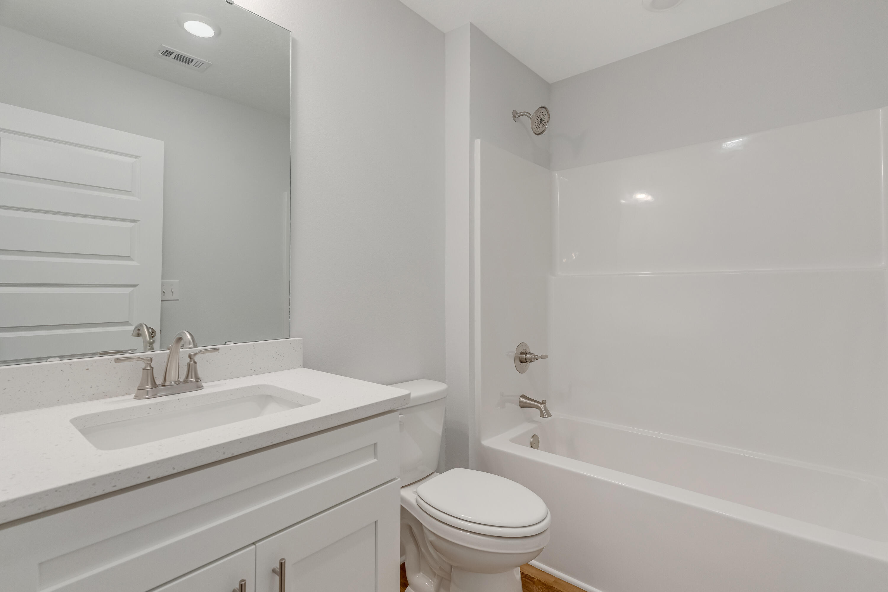 Bathroom with a white vanity, toilet, and tub-shower with brushed-nickel fixtures.