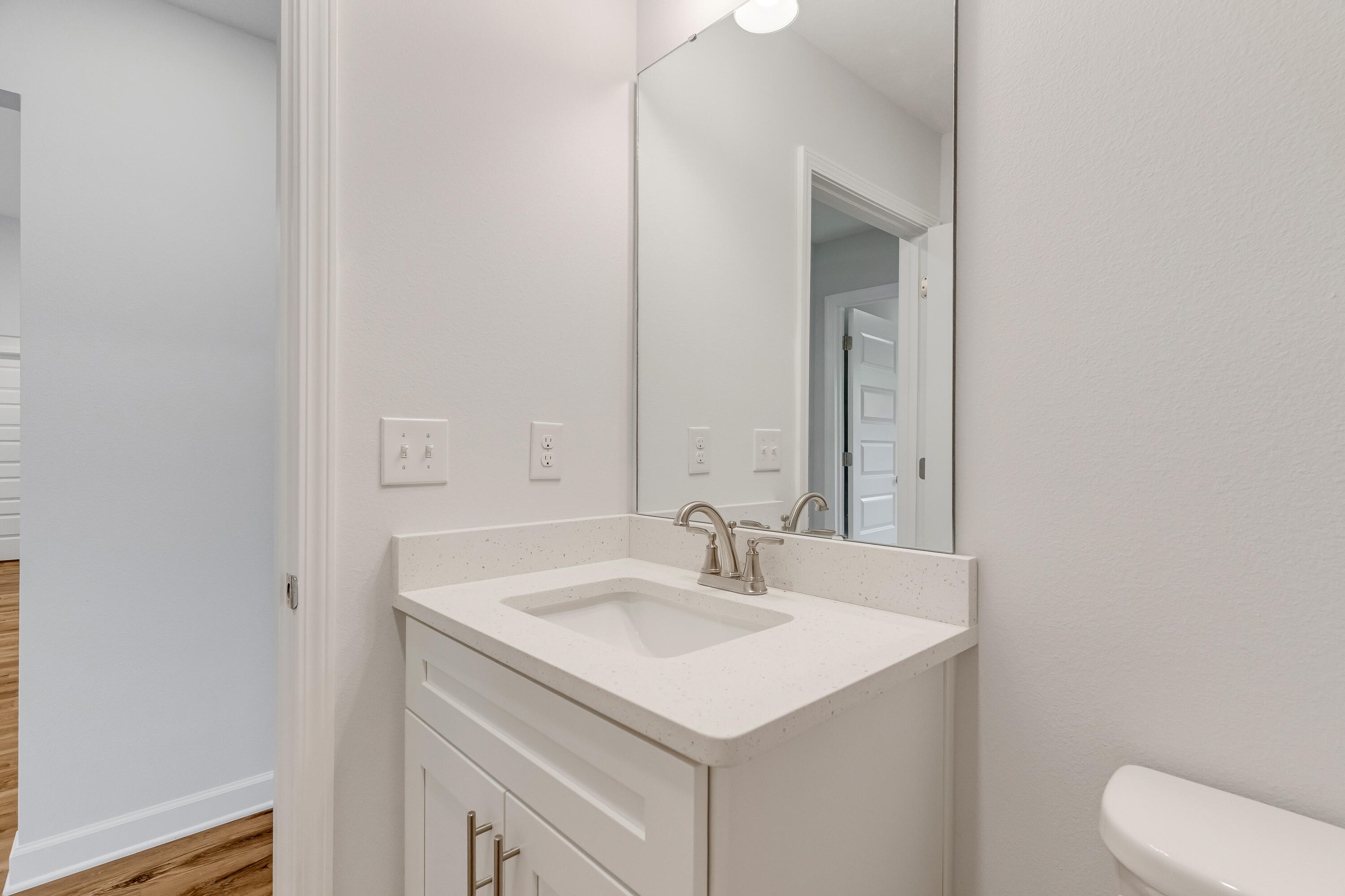 Bathroom vanity with a speckled countertop, inset sink, brushed metal faucet, and large mirror.