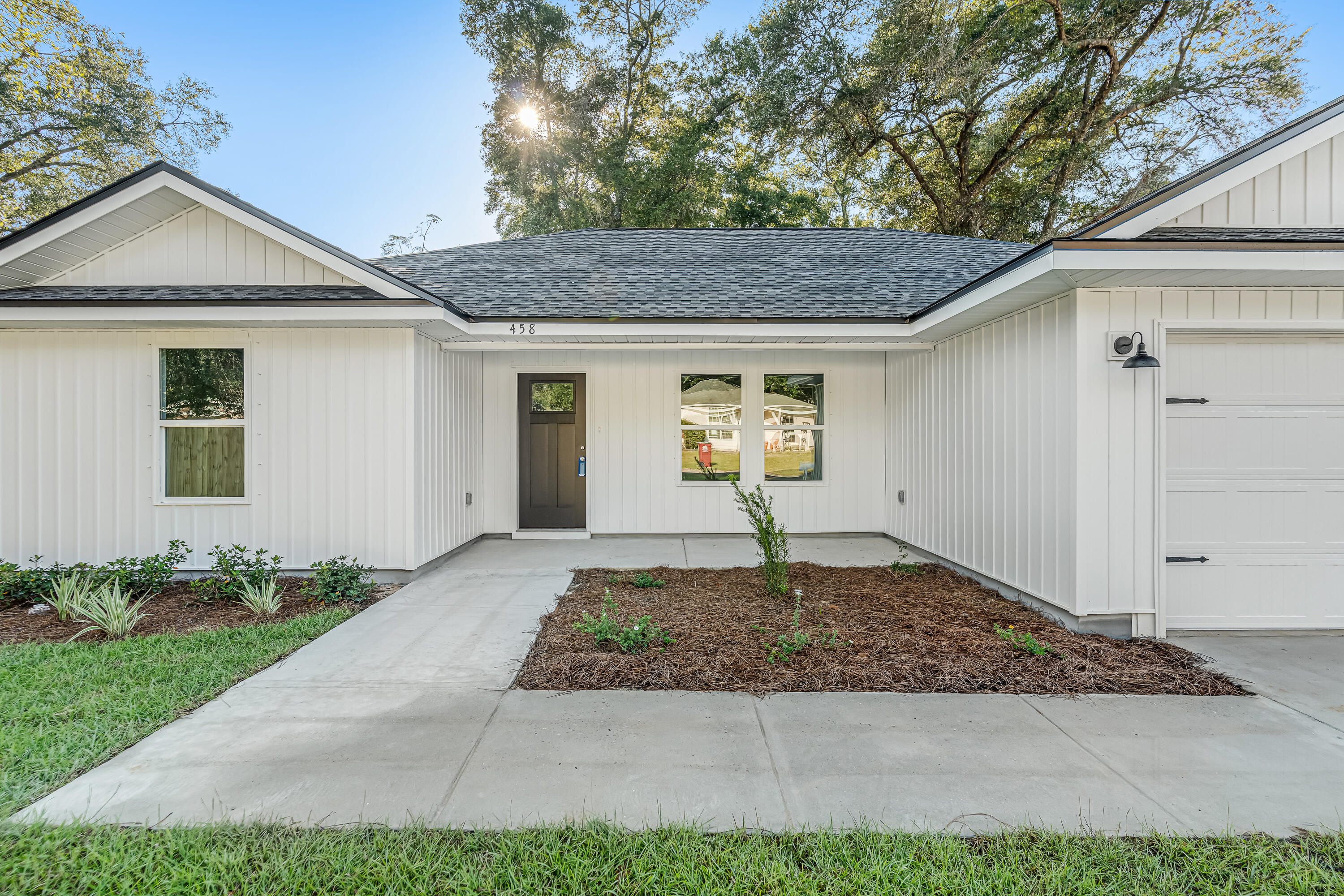 White single-story house with a recessed entry, attached garage, and landscaped front beds.