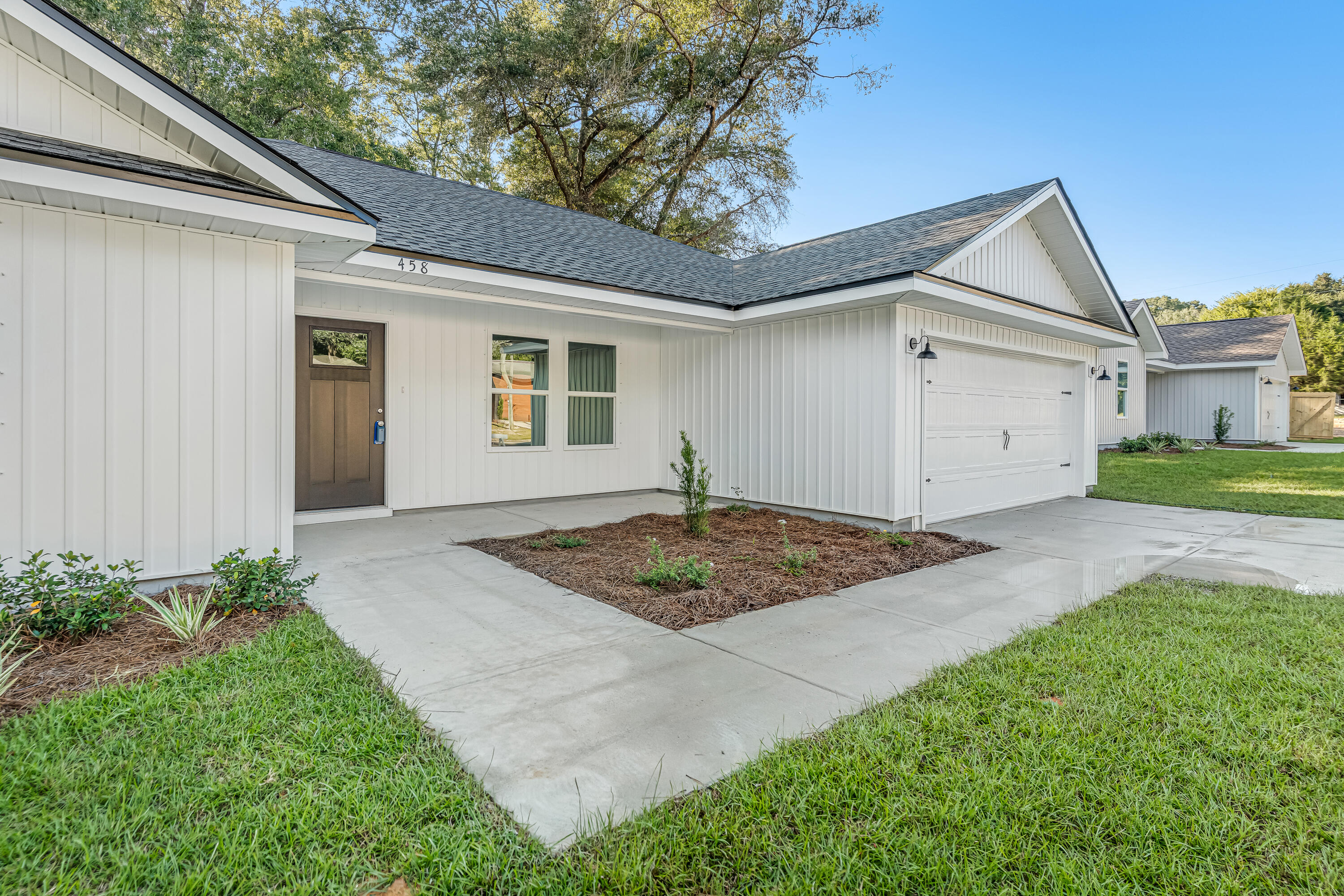 White single-story home with a covered entry, attached garage, and landscaped driveway.