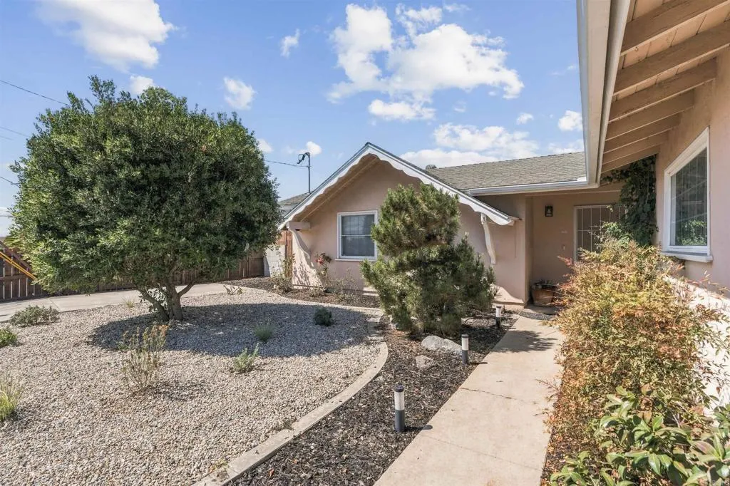 Single-story stucco home with a gravel front yard and curved walkway to the covered entry.