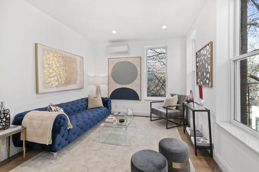 Living room with a blue tufted sofa, glass coffee table, and large windows.