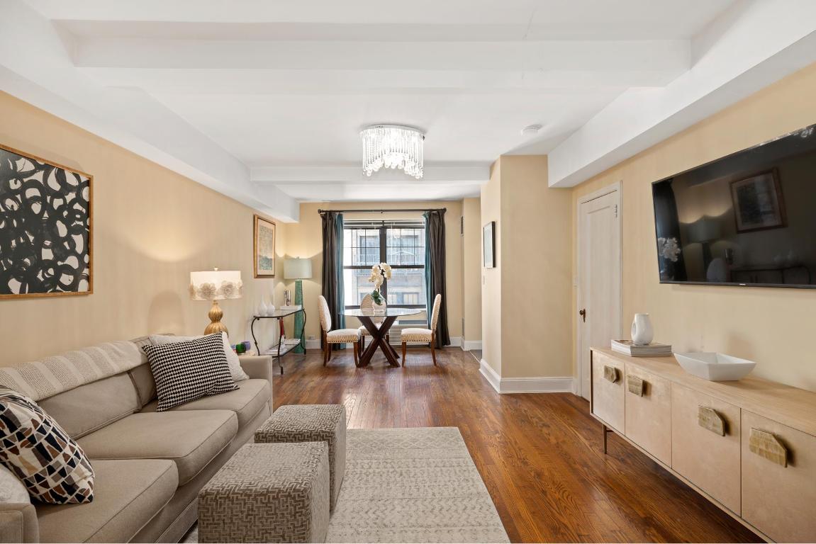 Living room with a beige sectional sofa, hardwood floors, and a dining nook beside the window.