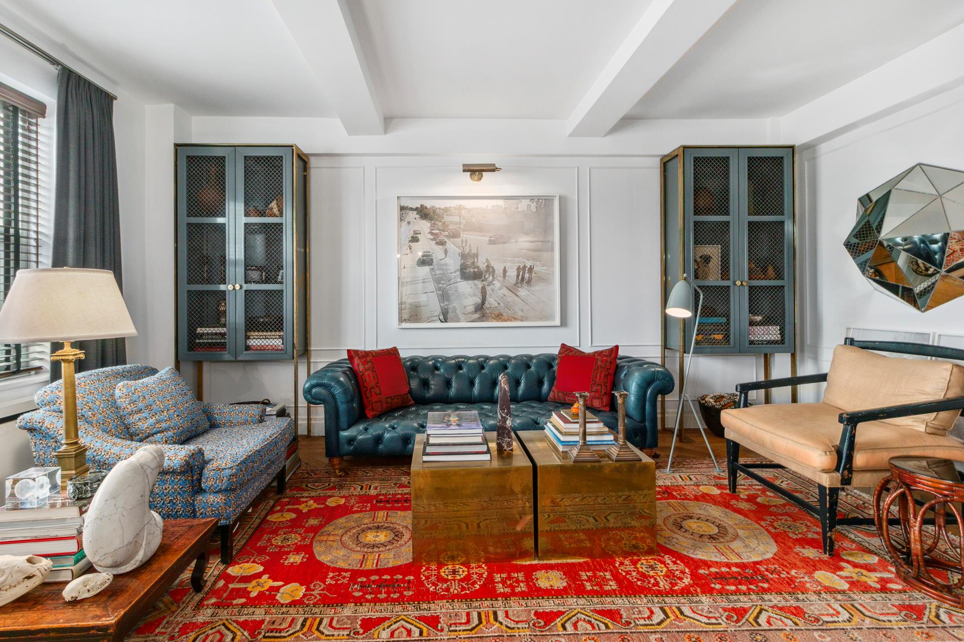 Furnished living room with a teal tufted sofa, blue display cabinets, and layered patterned rugs.