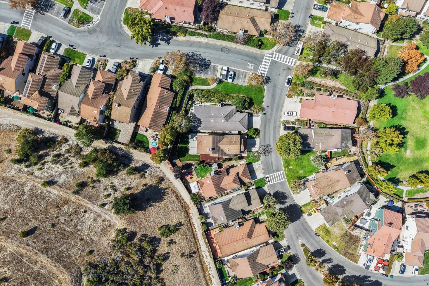 Aerial view of a residential neighborhood bordered by undeveloped open land.