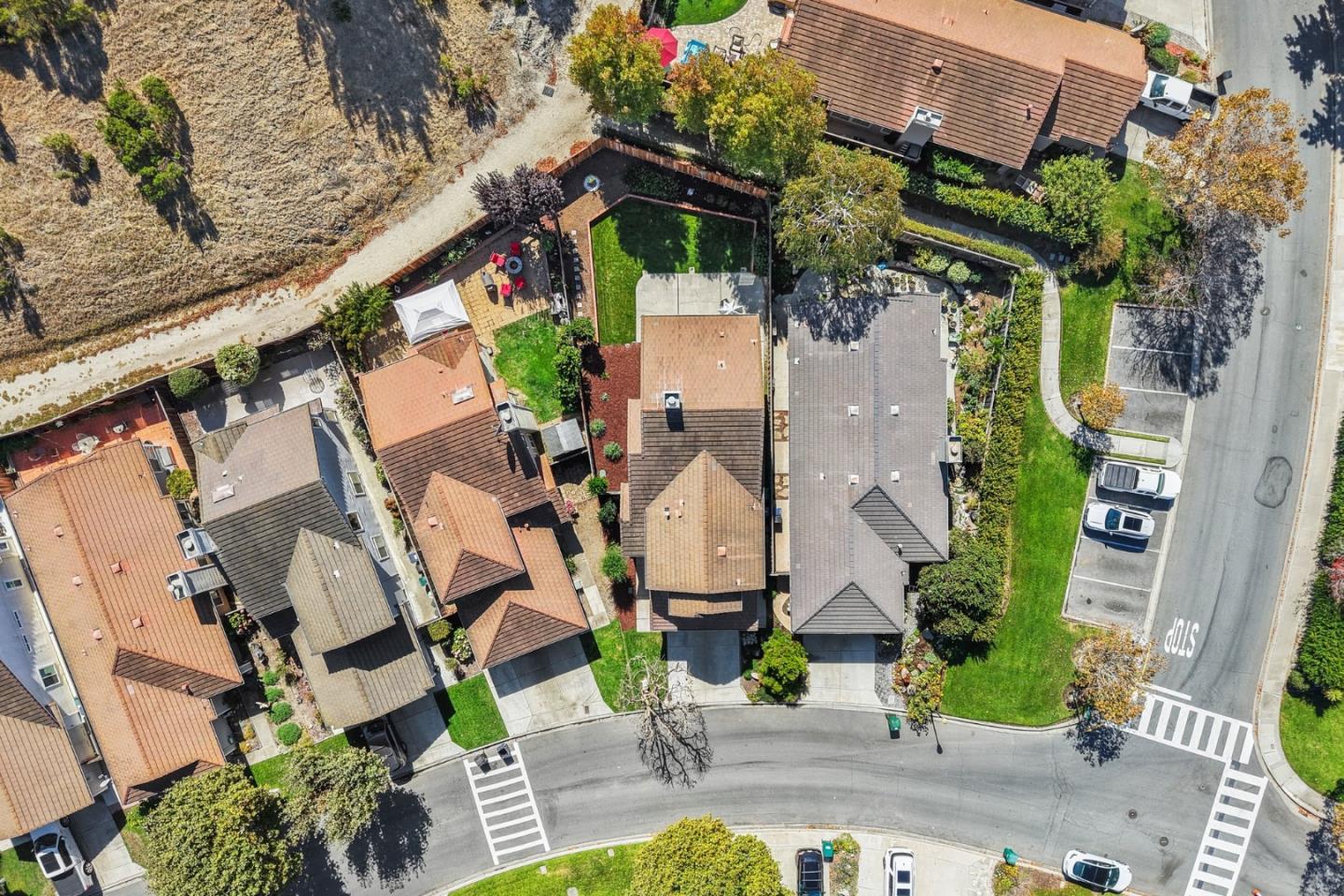 Aerial view of homes and landscaped yards beside a dry open field and intersecting streets.