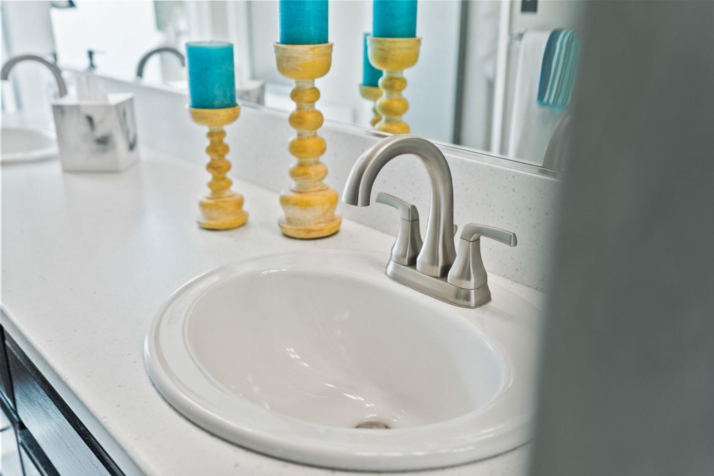 Bathroom sink with a brushed-nickel faucet and turquoise candles on gold holders.