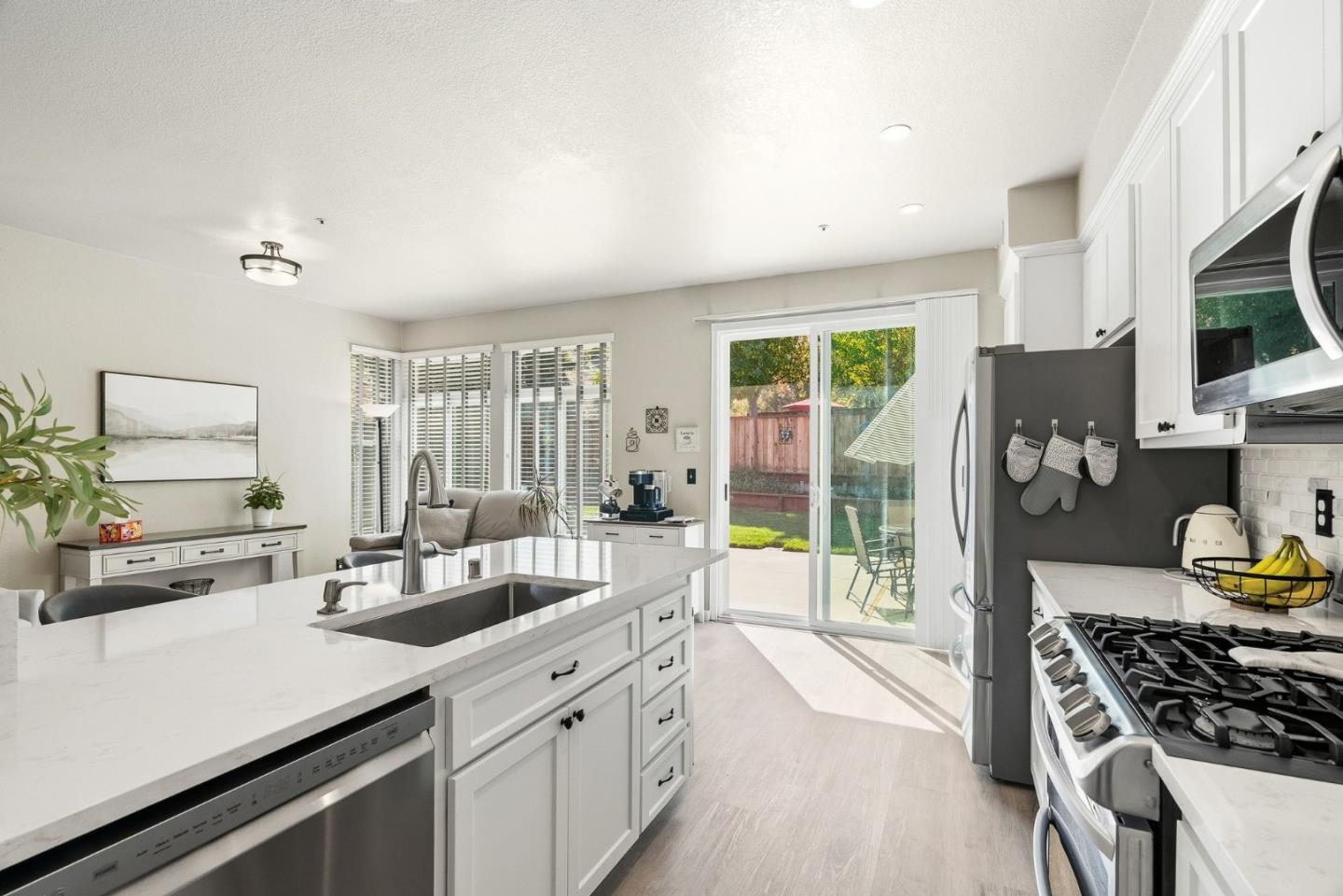 Bright kitchen with a large quartz island, stainless steel appliances, and sliding glass doors to the backyard.