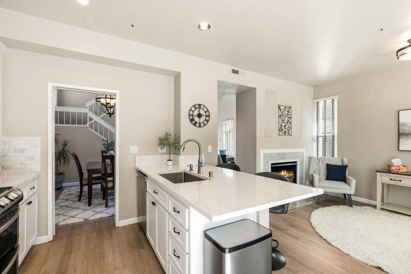 Kitchen with a large white island and sink, open to a living room with a fireplace.