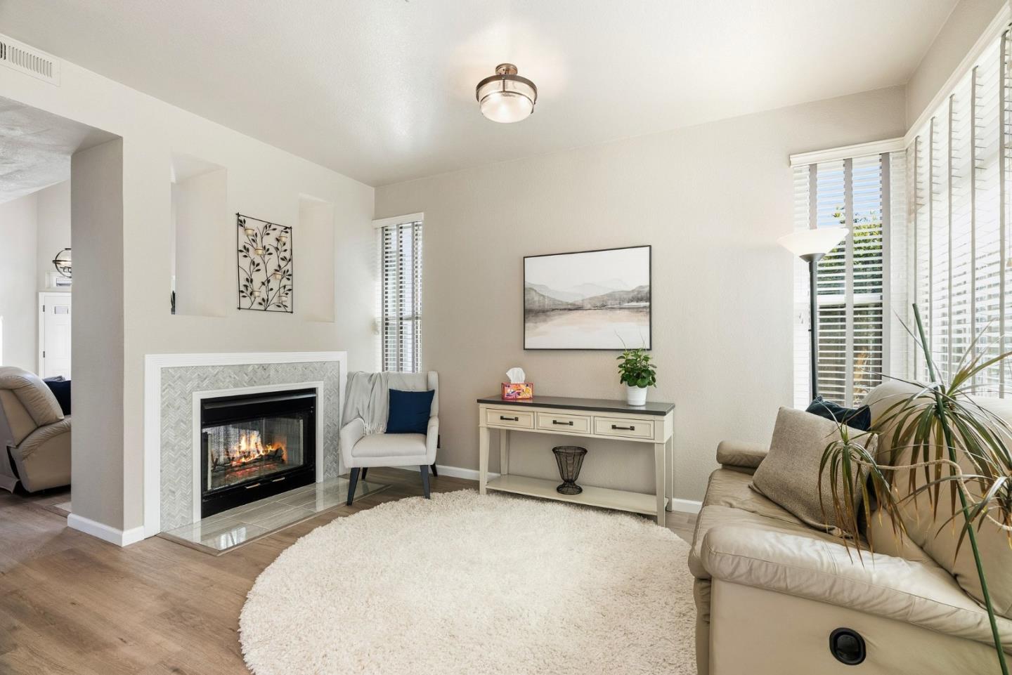 Living room with a tiled fireplace, light sofas, and large shuttered windows.