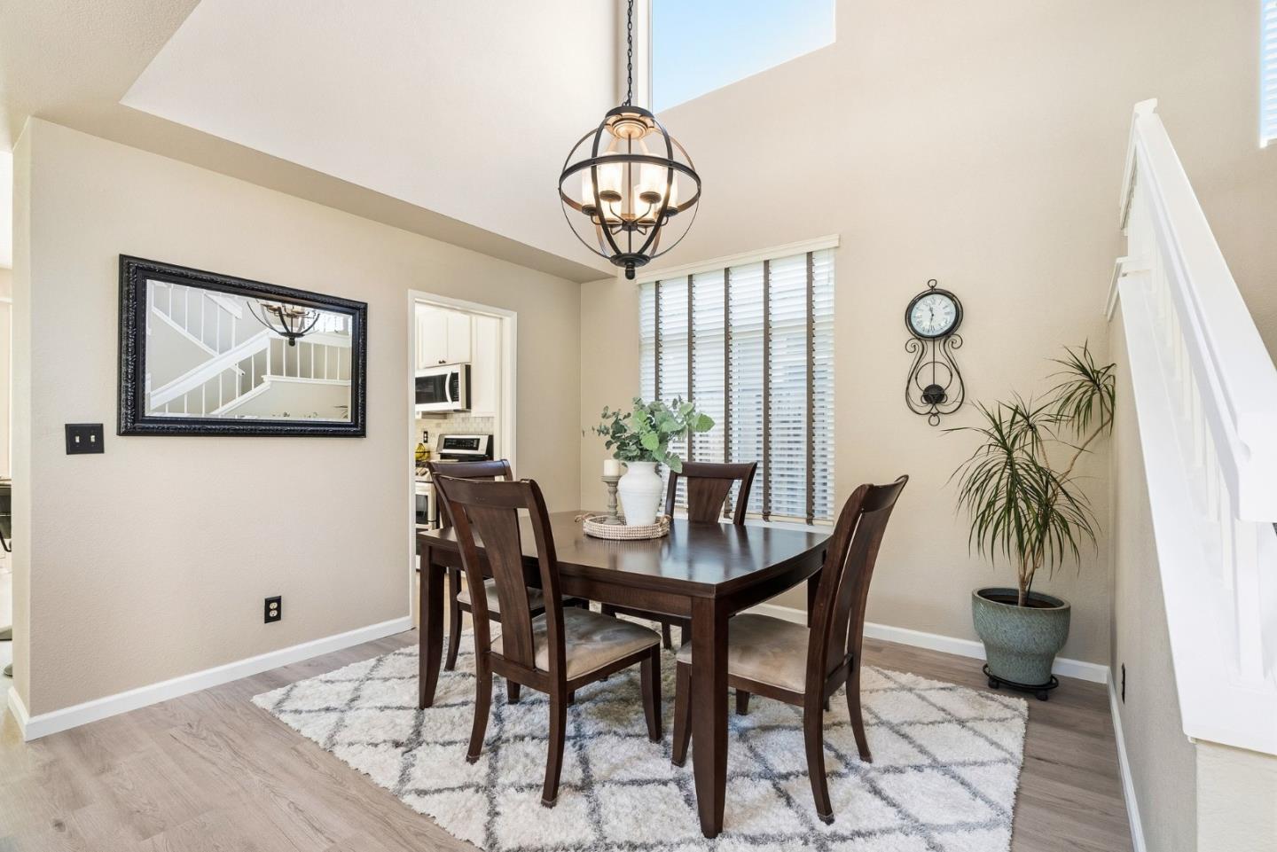 Dining room with a dark wood table, chandelier, patterned rug, and staircase.