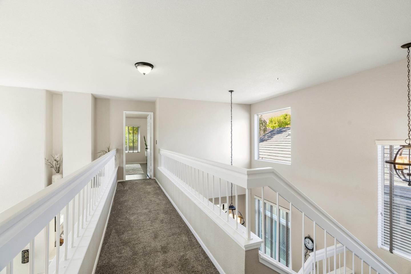 Carpeted upstairs landing with white railings overlooking the home's lower level.