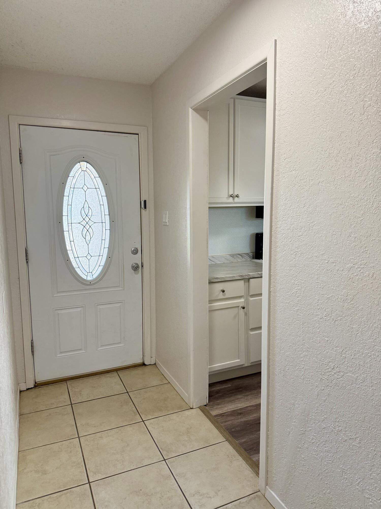 Entryway with a decorative glass front door, tiled floor, and built-in cabinets.