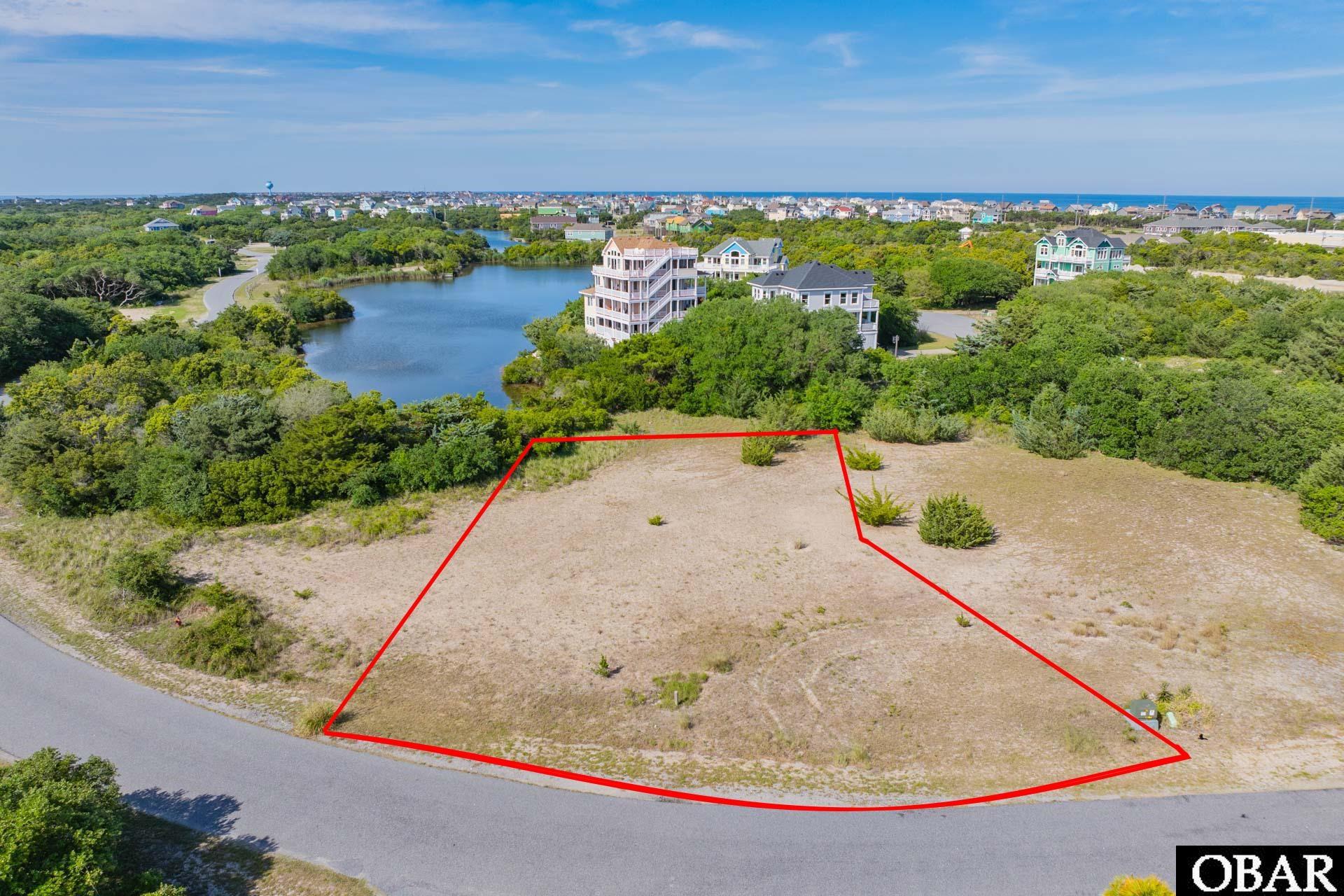 Vacant coastal lot outlined in red, with a pond and ocean visible beyond.