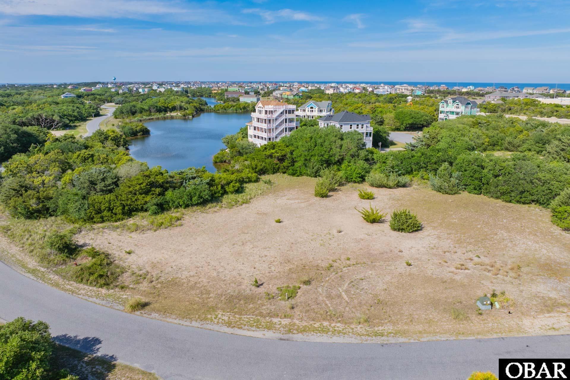 Vacant lot beside a lagoon, with nearby homes and the ocean on the horizon.