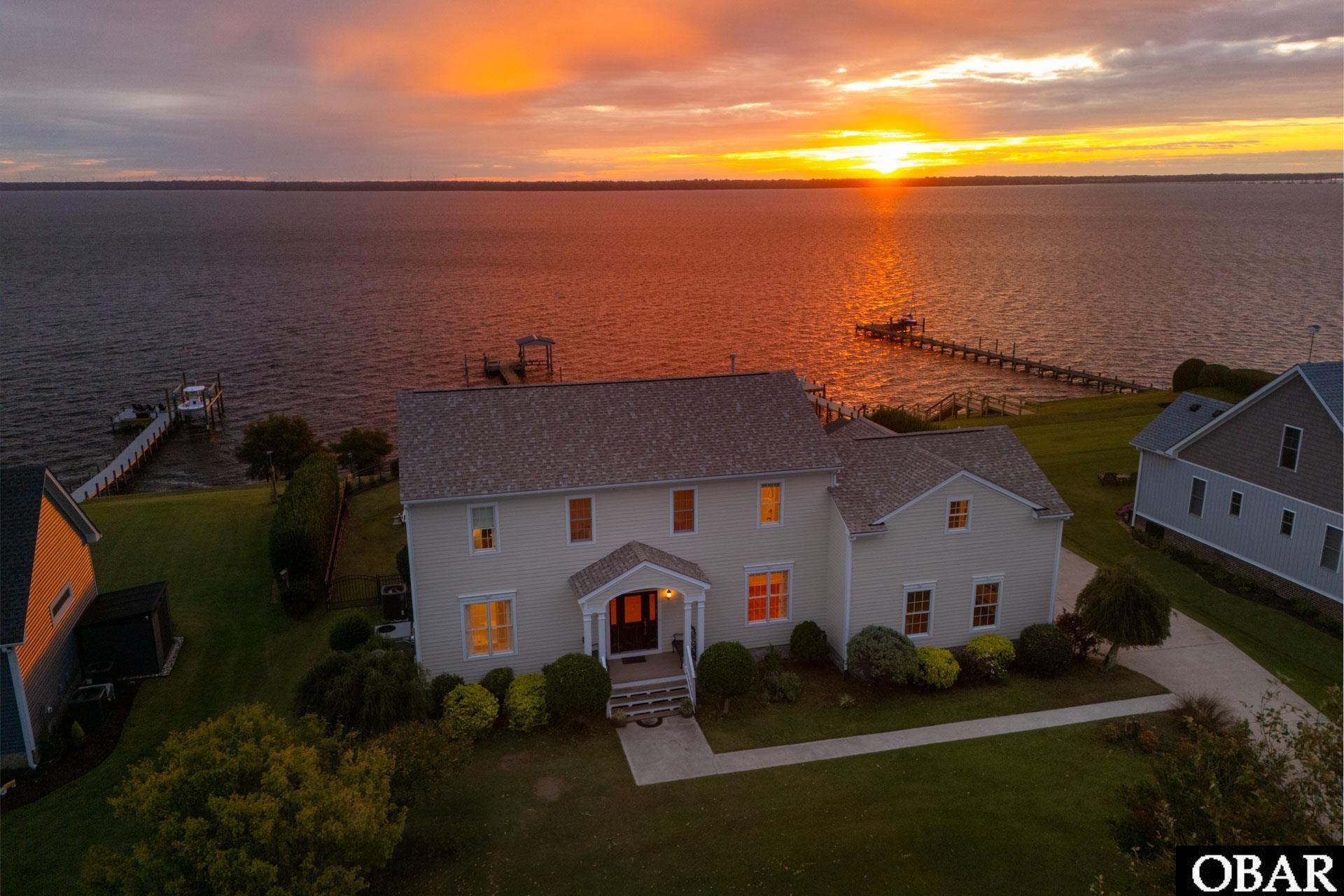 Waterfront home and private docks beside sunset-lit water.