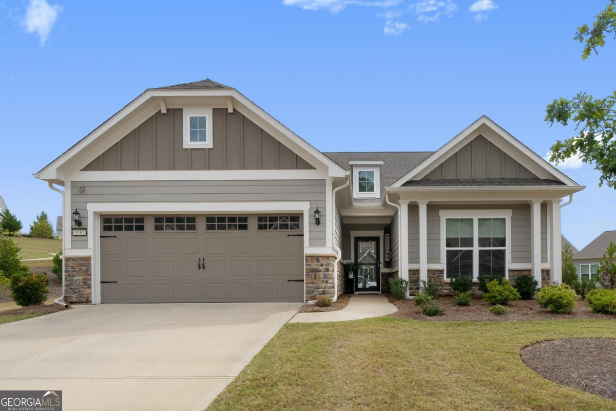 Gray home with a double garage, stone accents, and a broad concrete driveway.