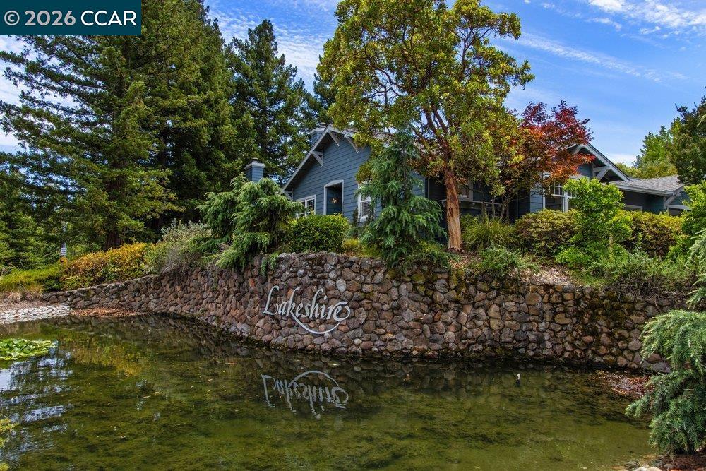 Blue-gray house behind a stone Lakeshire wall beside a pond.