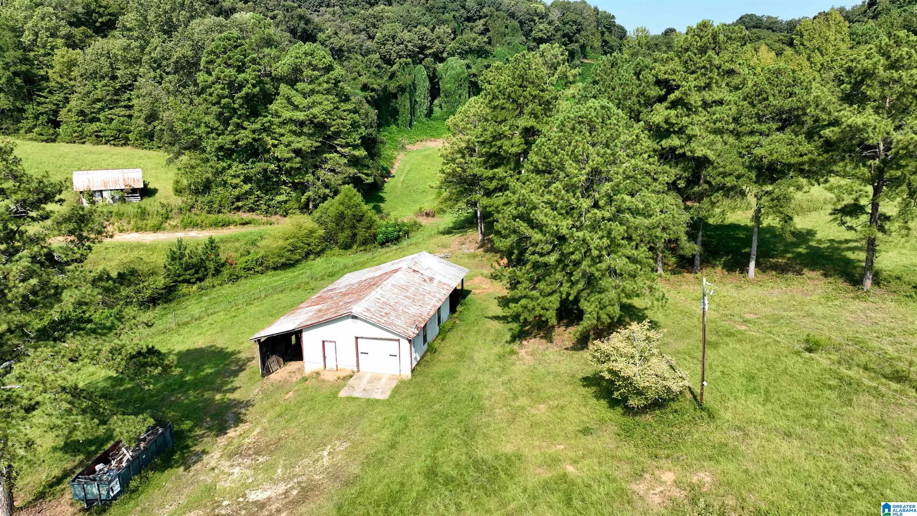 Aerial view of a detached garage on a grassy, tree-lined property.