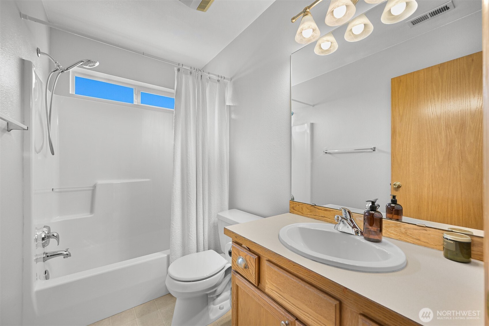 Bathroom with a tub and shower, wood vanity, oval sink, and large mirror.