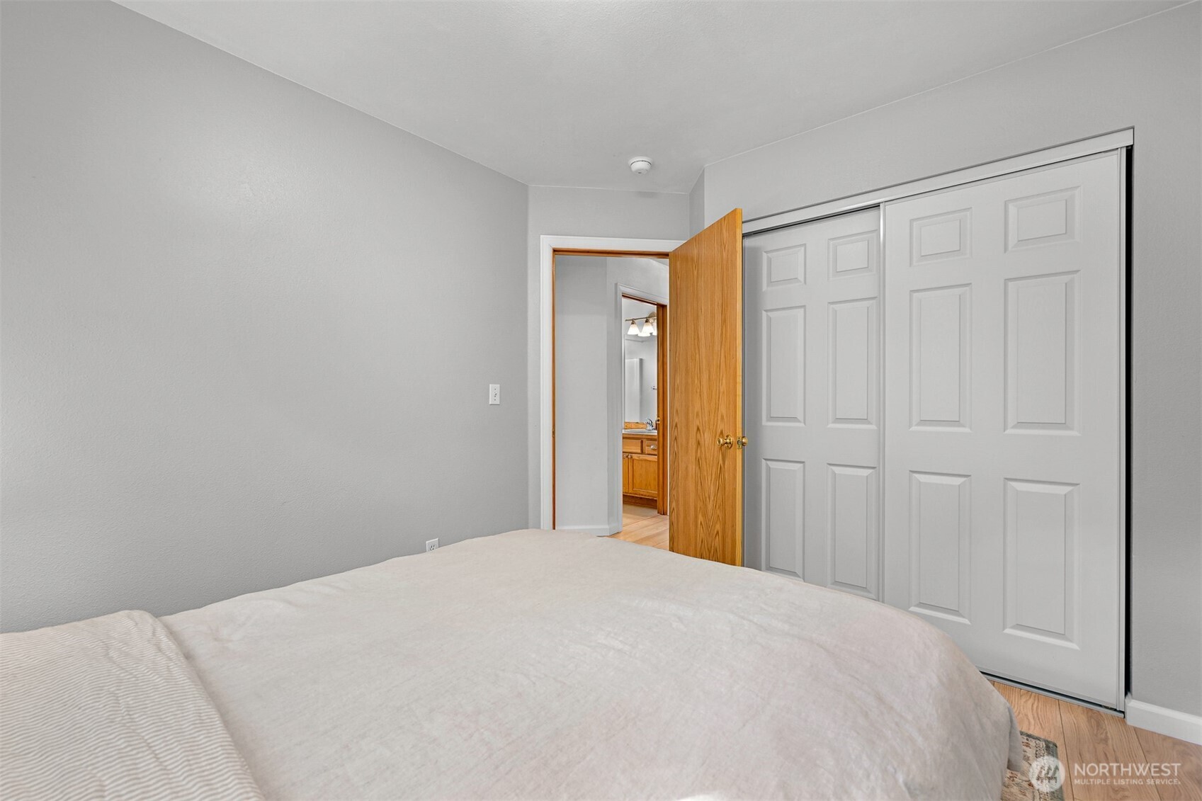 Bedroom with a bed, large sliding closet doors, and an open doorway to a bathroom.
