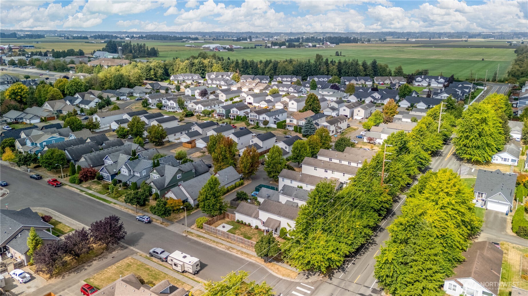 Aerial view of a residential neighborhood bordered by farmland, with tree-lined streets and broad fields.