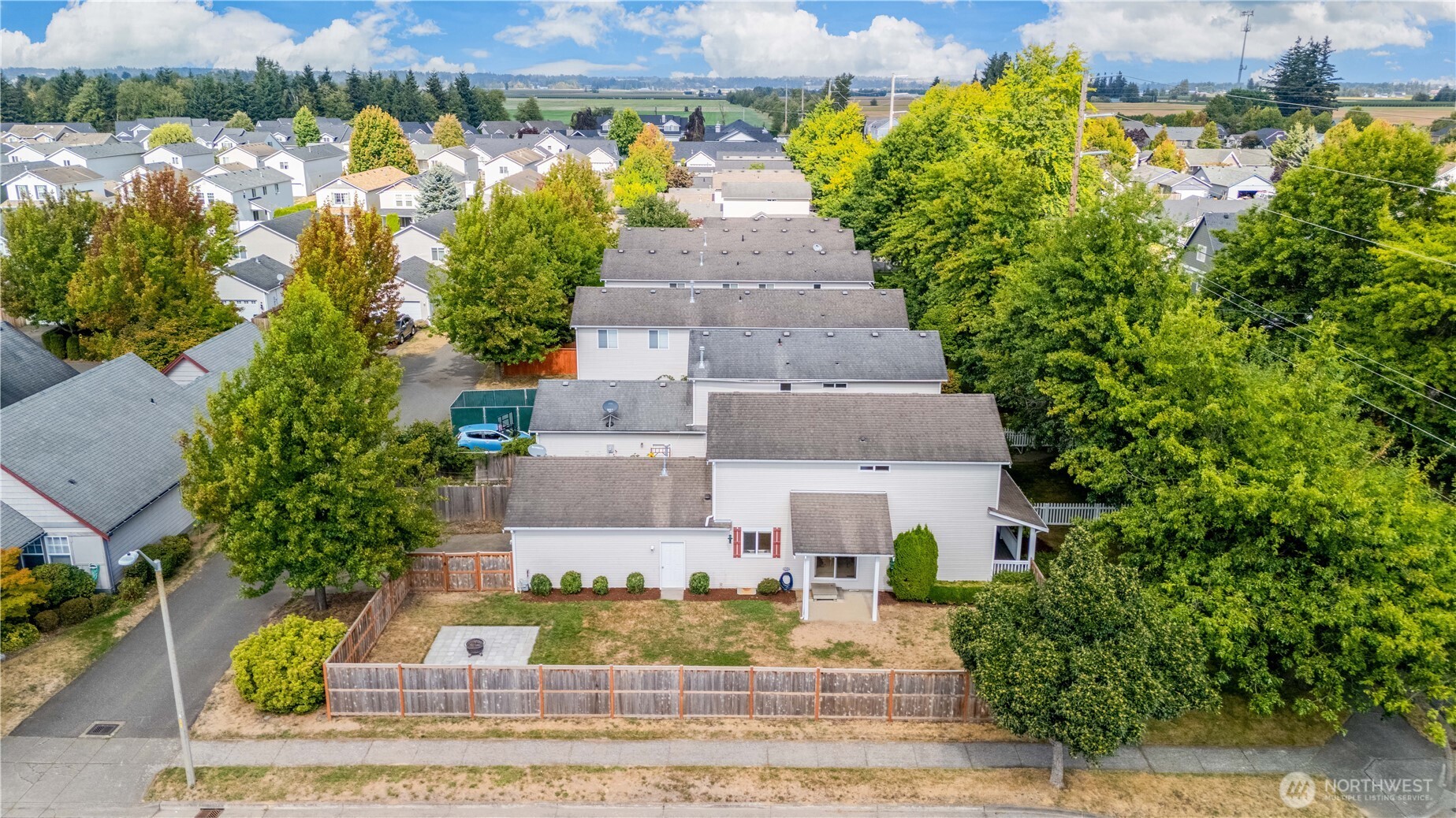 Aerial view of a two-story home with a fenced backyard and paved patio.