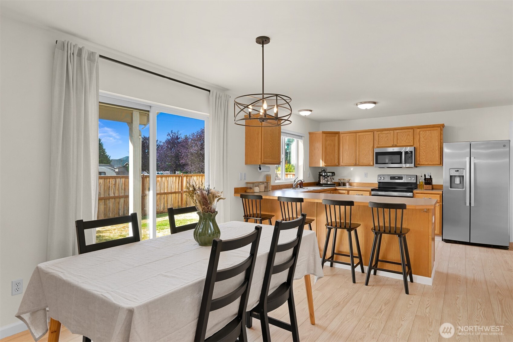 Kitchen and dining area with a breakfast bar, stainless appliances, and sliding doors to a fenced yard.