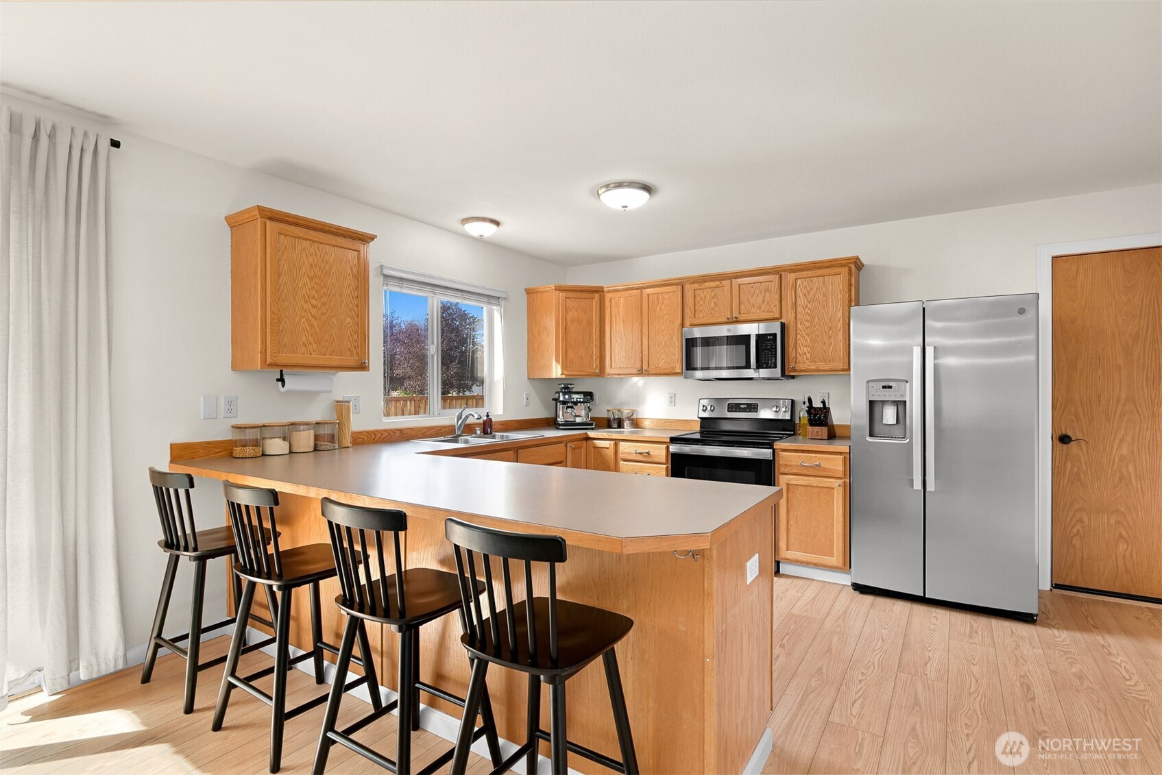 Kitchen with a large breakfast bar, wood cabinetry, and stainless steel appliances.