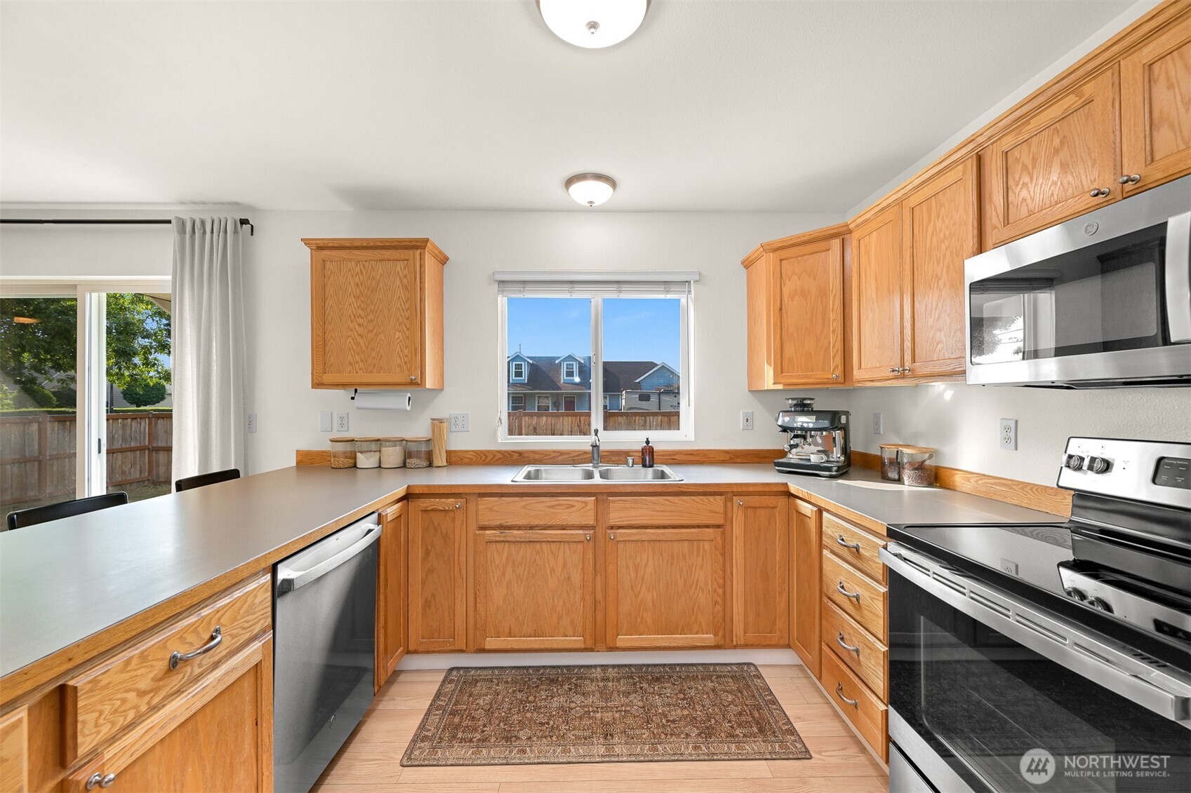 Kitchen with honey-oak cabinets, stainless steel appliances, and a window above the sink.