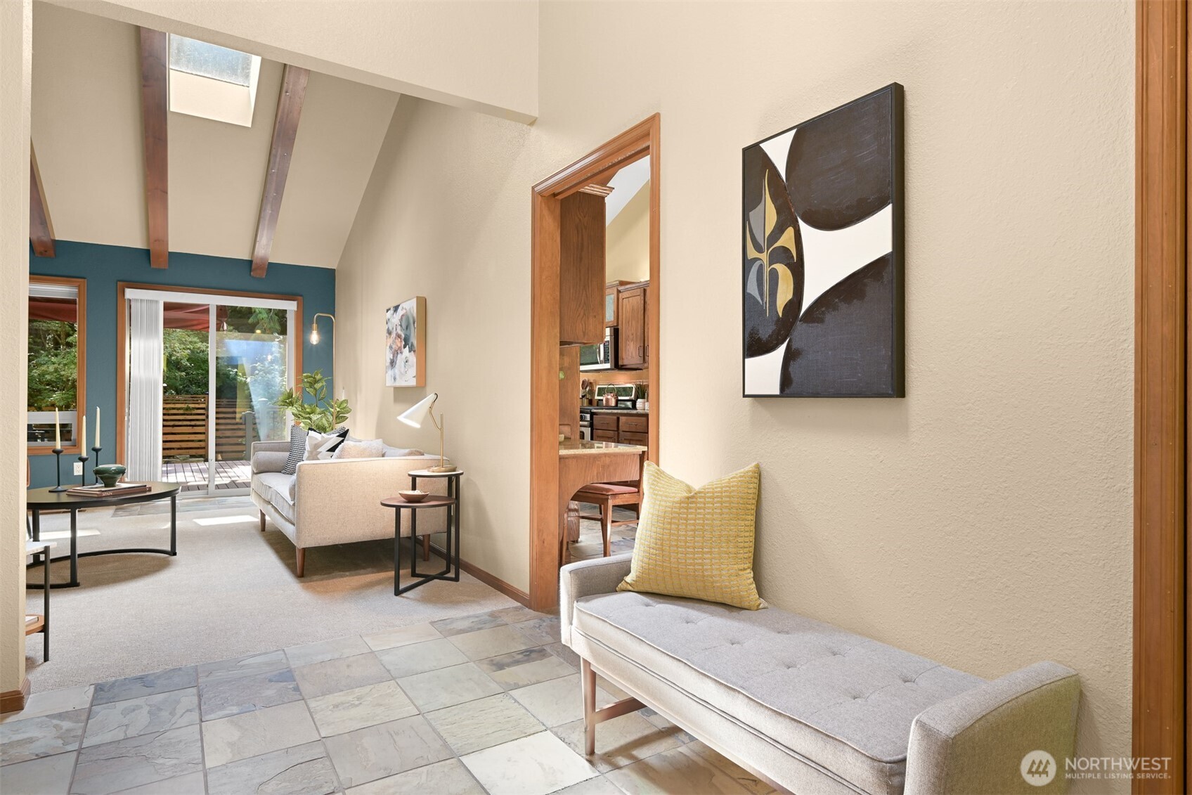 Living room with vaulted wood-beam ceiling, teal accent wall, and sliding doors to a deck.