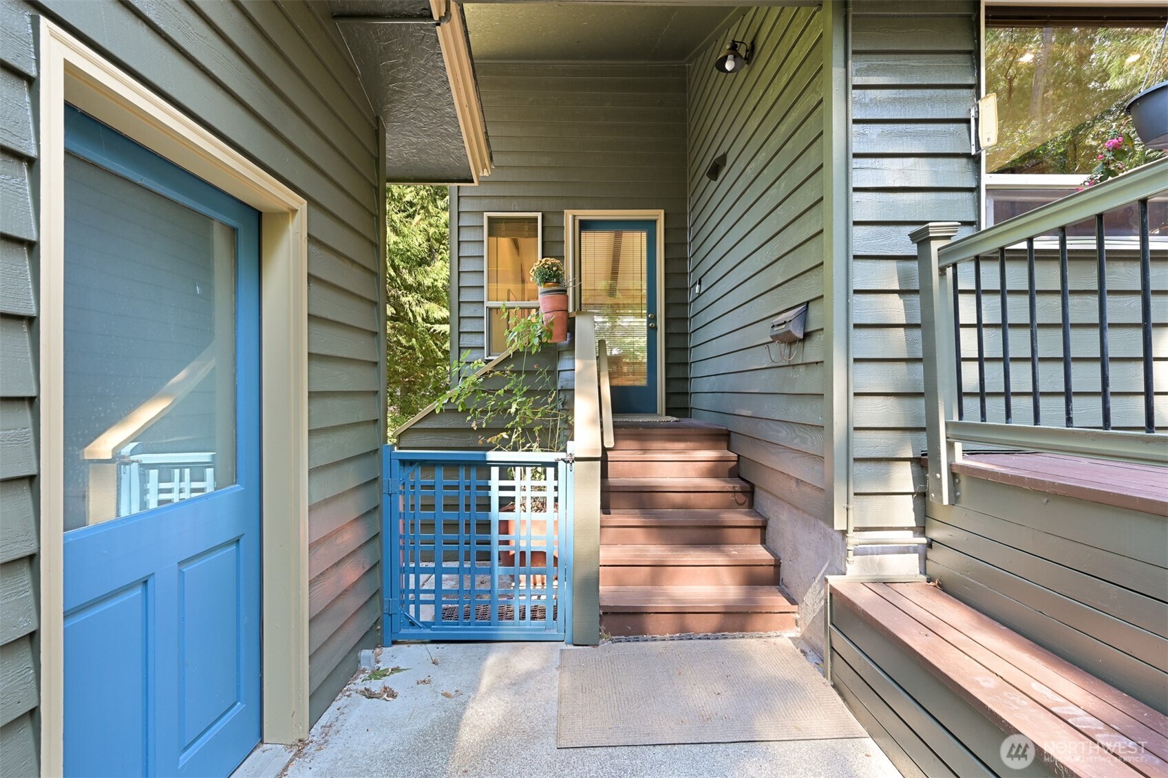 Covered home entry with brown steps leading to a blue front door and blue railings.