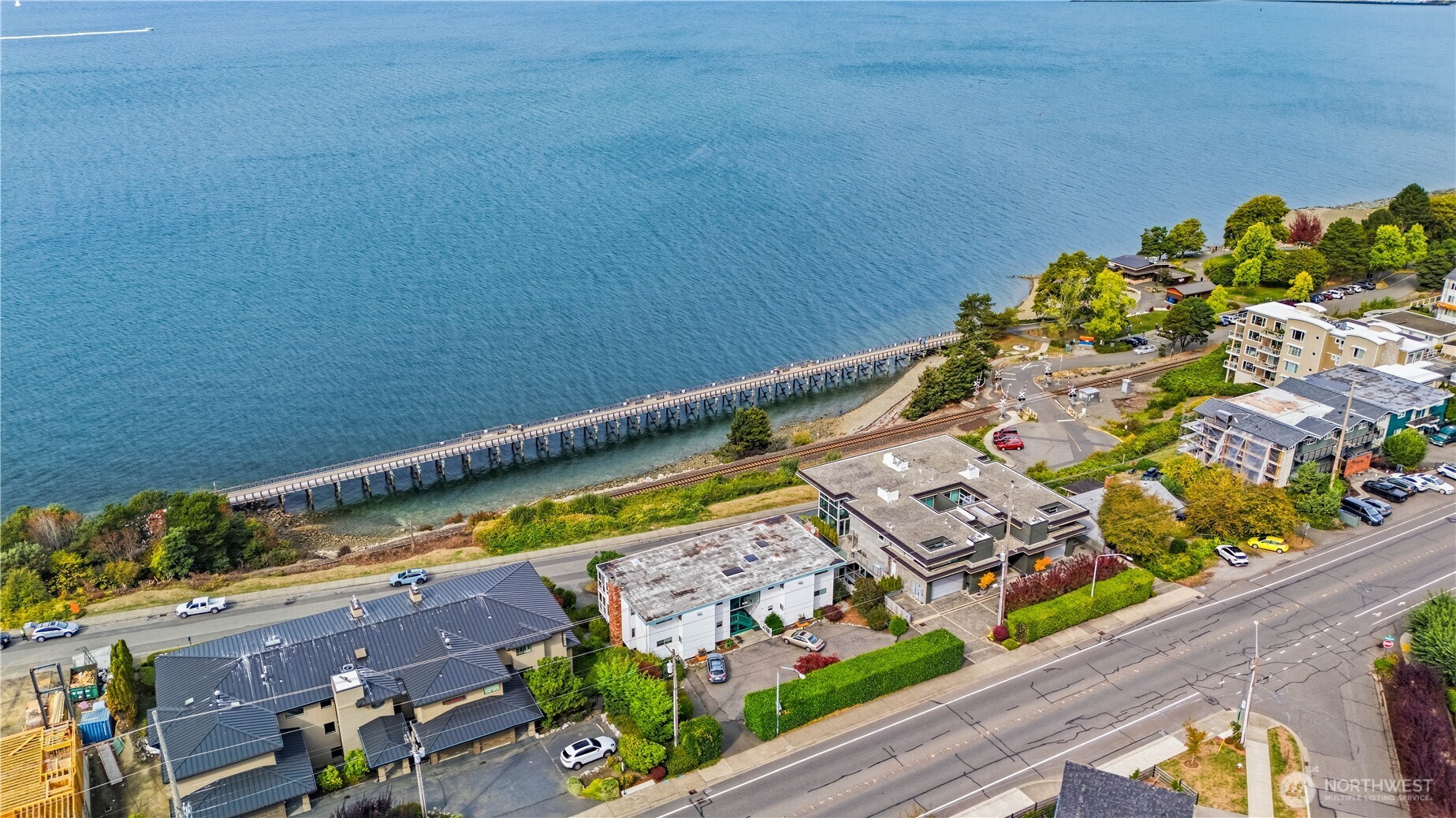 Waterfront neighborhood beside a broad bay, with a long pier tracing the shoreline.