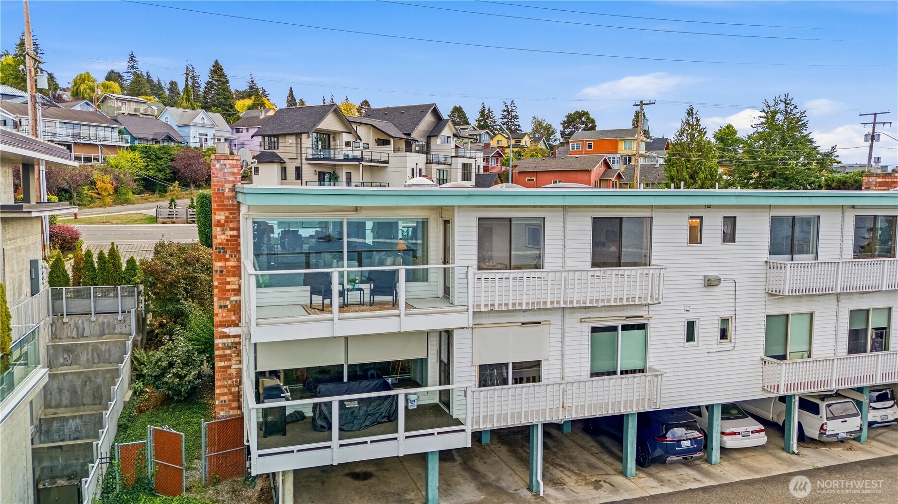 Condominium building with glass-enclosed balconies and covered parking, viewed from above.