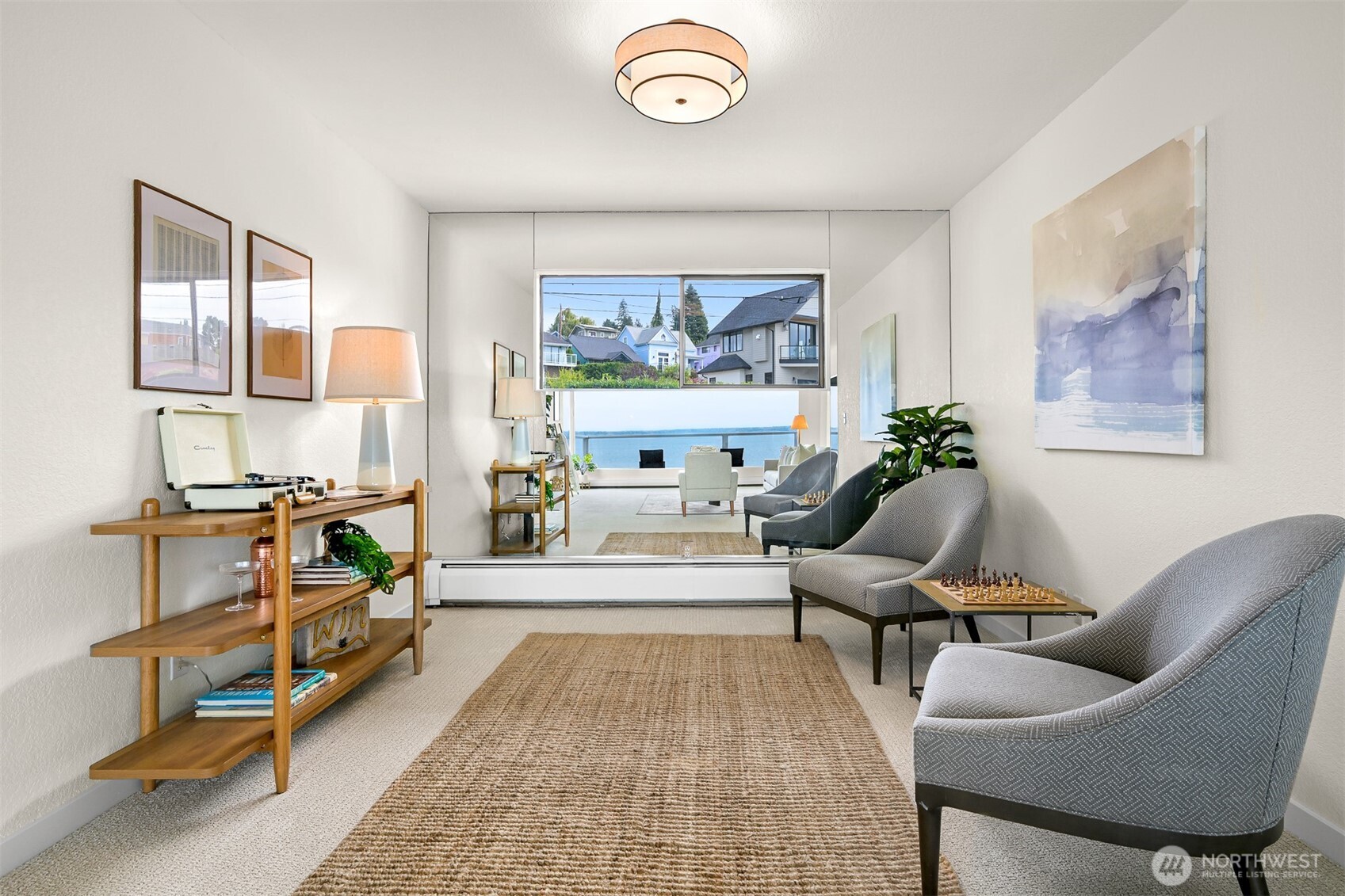Furnished living room with gray armchairs and a water view through the windows.