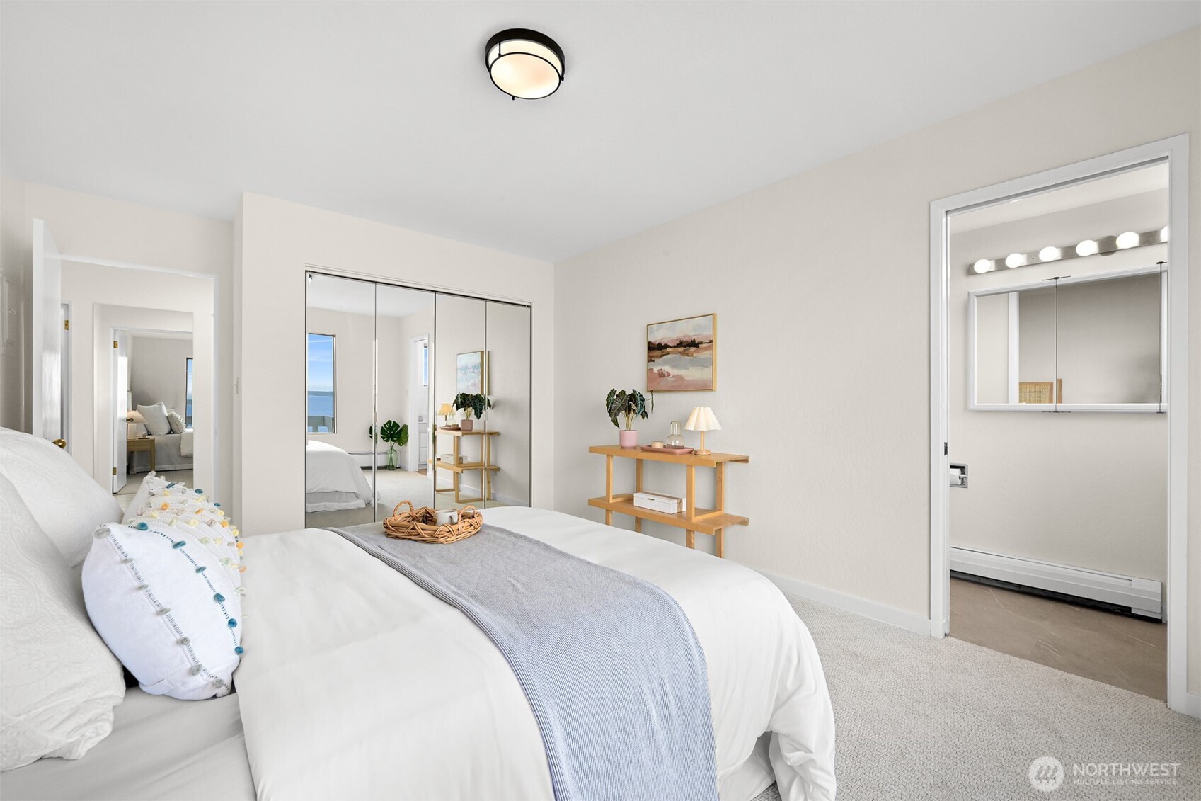 Furnished bedroom with mirrored closet doors and a glimpse of water in the mirror.