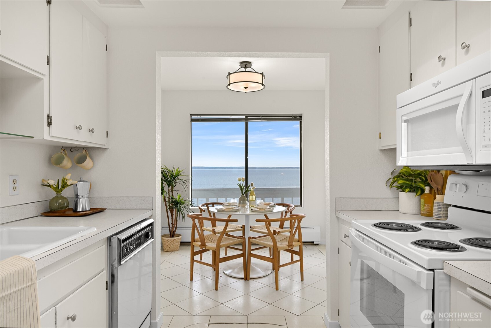 White kitchen and dining nook with a large window overlooking the water.
