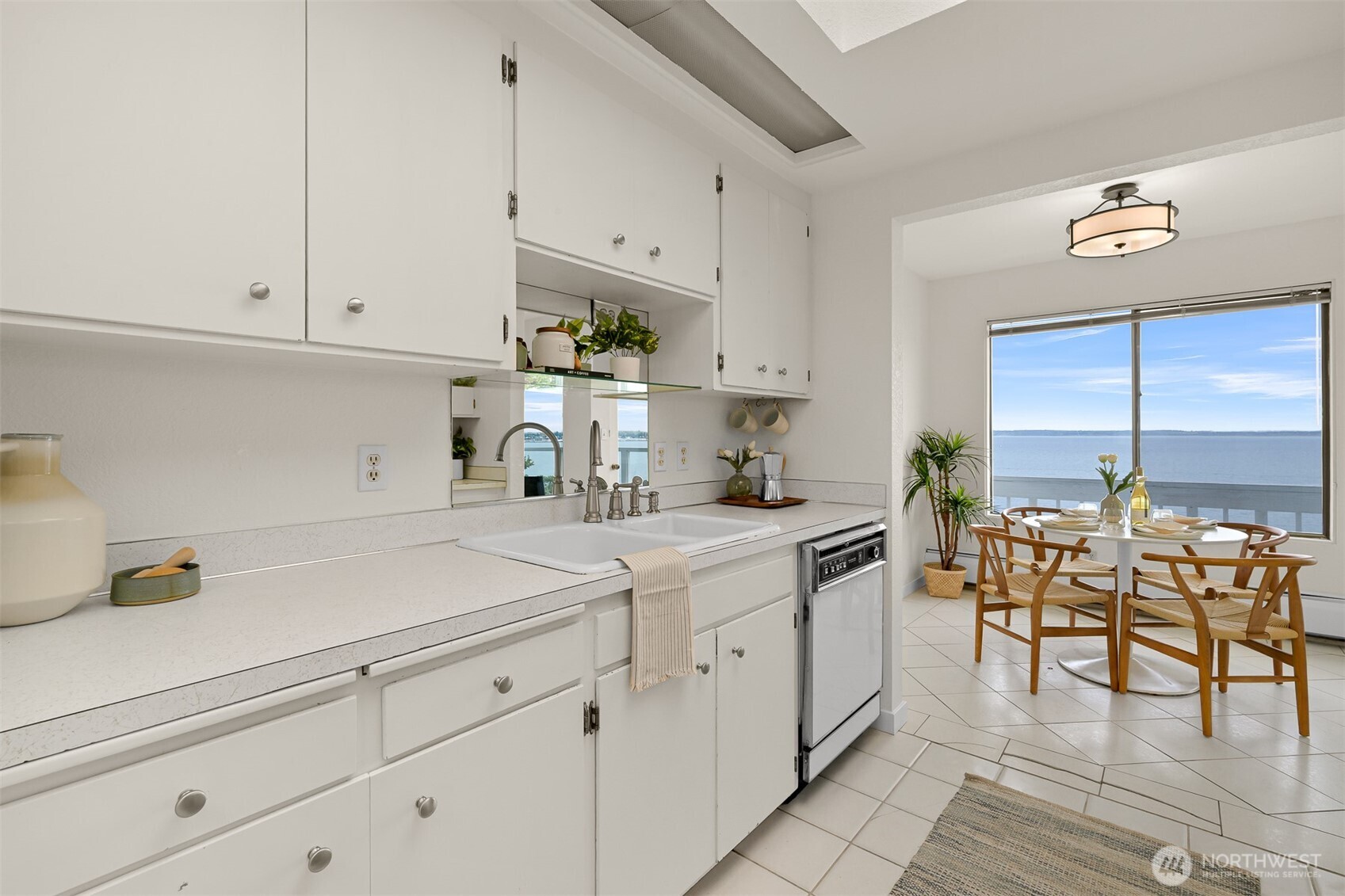 Bright white kitchen and dining area with large windows overlooking the water.