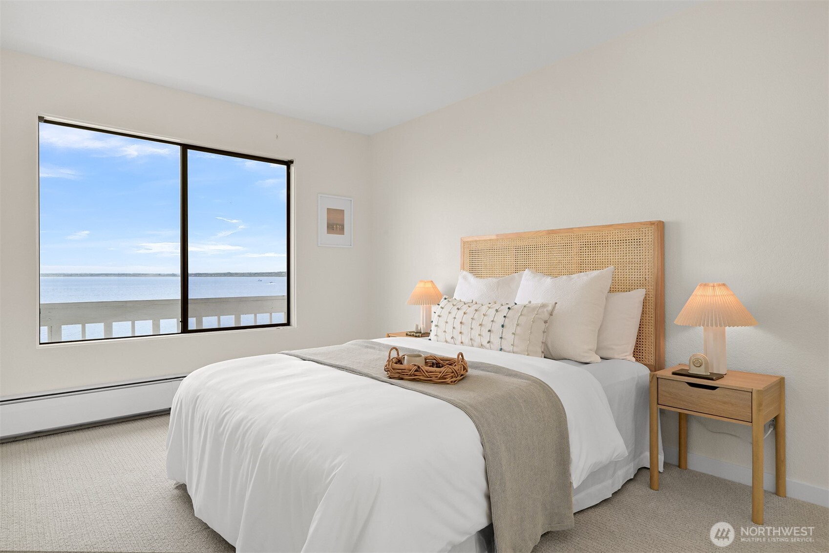Bedroom with a woven headboard and a large window overlooking the water.