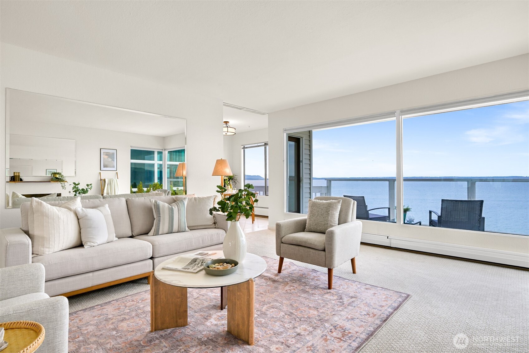 Furnished living room with large windows overlooking the water and balcony.