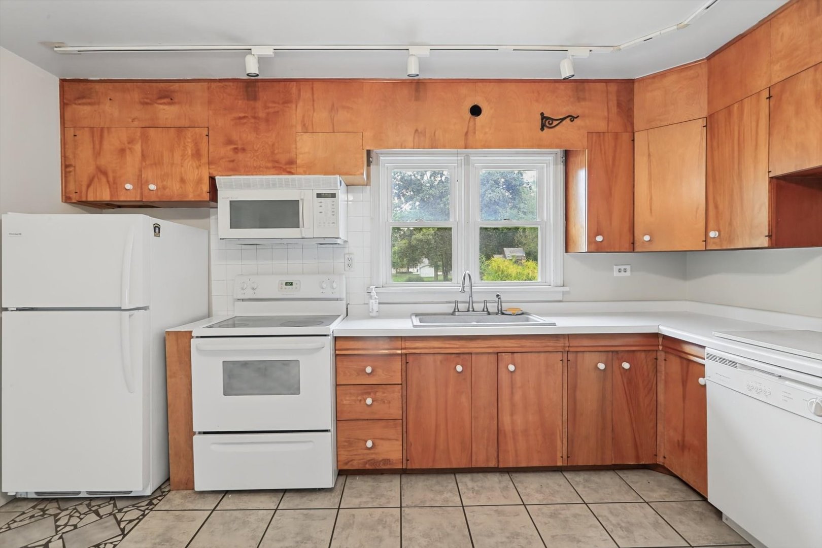 Kitchen with wood cabinets, white appliances, and a double window above the sink.