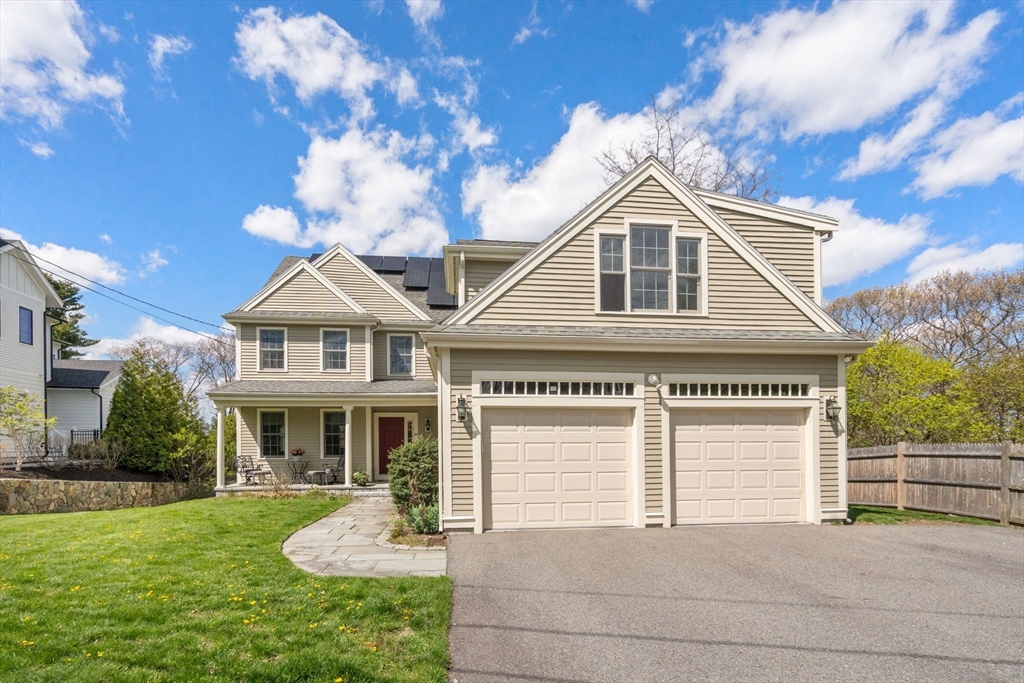 Beige two-story house with a double garage, solar panels, and a curved front walkway.