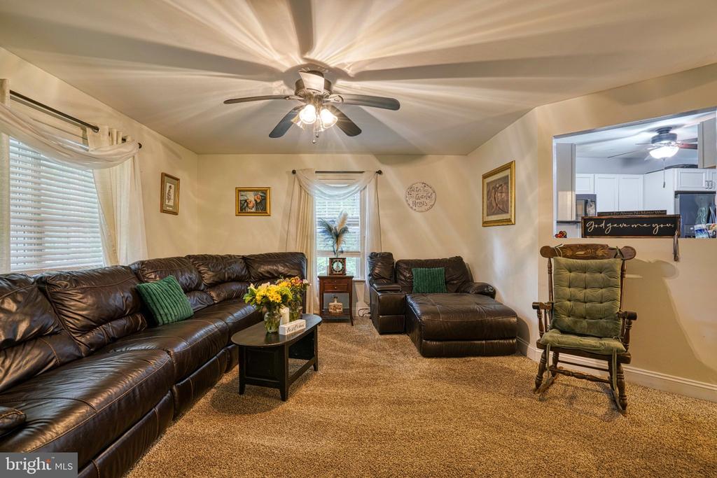 Living room with a leather sectional, matching chaise, and green rocking chair beside an open kitchen.