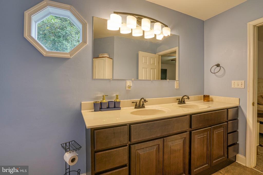 Bathroom with a dark wood double vanity, two sinks, and an octagonal window.