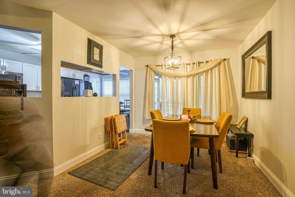 Dining room with a dark table, mustard-colored chairs, chandelier, and curtained windows.