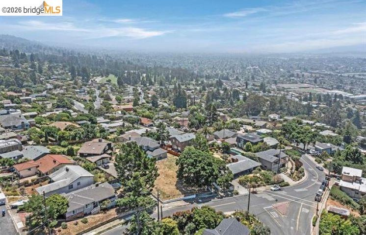 Aerial view of a hillside neighborhood with winding streets and homes among trees.