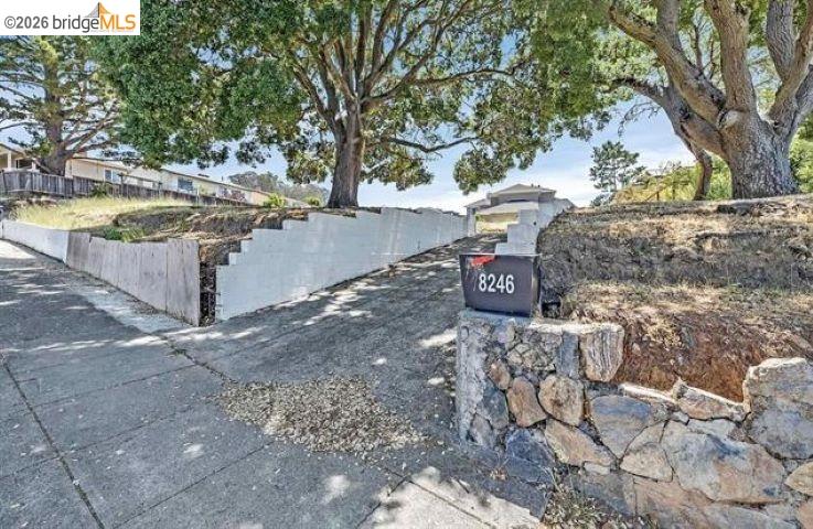 Home entrance with sloped driveway, stone retaining wall, and mailbox marked 8246.