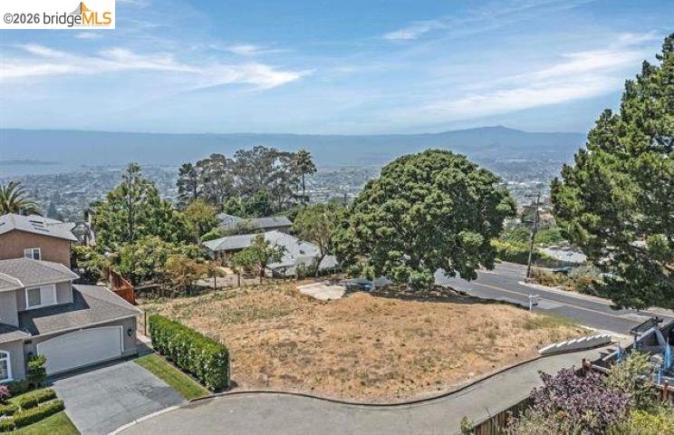 Vacant hillside lot with neighboring homes and a wide valley view.