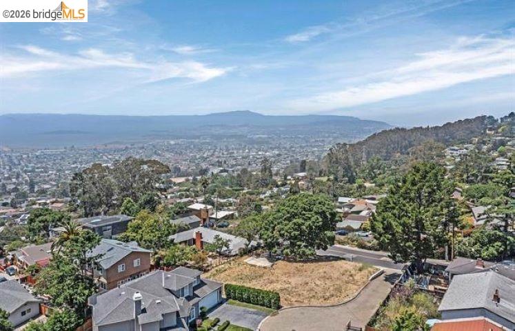 Elevated view over El Cerrito homes and trees, with distant hills on the horizon.